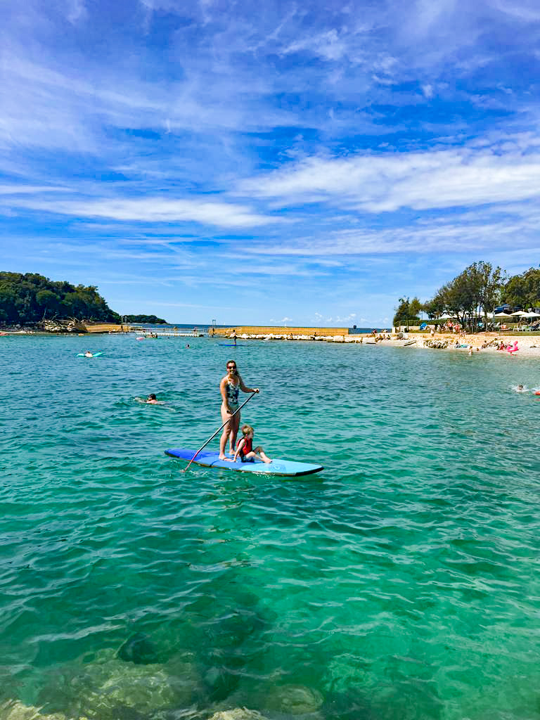 Family Paddle boarding in clear blue sea at luxury family campsite in Croatia. Europe's best campsite.